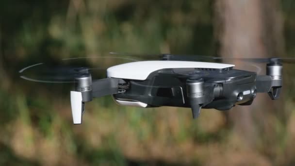 Drone with a camera hovers in the air. Quadcopter flies above the ground in the forest — Stock Video