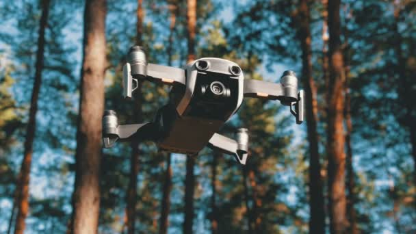 Drone με μια φωτογραφική μηχανή που αιωρείται στον αέρα. Τετράγωνο ελικόπτερο πετά πάνω από το έδαφος στο δάσος — Αρχείο Βίντεο
