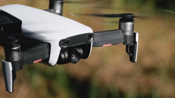 Drone με μια φωτογραφική μηχανή που αιωρείται στον αέρα. Τετράγωνο ελικόπτερο πετά πάνω από το έδαφος στο δάσος — Αρχείο Βίντεο