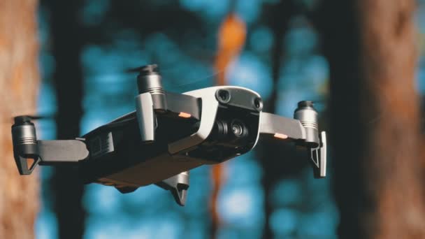 Drone con una cámara se cierne en el aire. Quadcopter vuela sobre el suelo en el bosque — Vídeo de stock