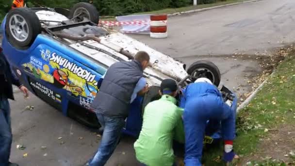 Глядачі допомогти перевернути ралійного автомобіля на даху. Аварії з ралійного автомобіля — стокове відео