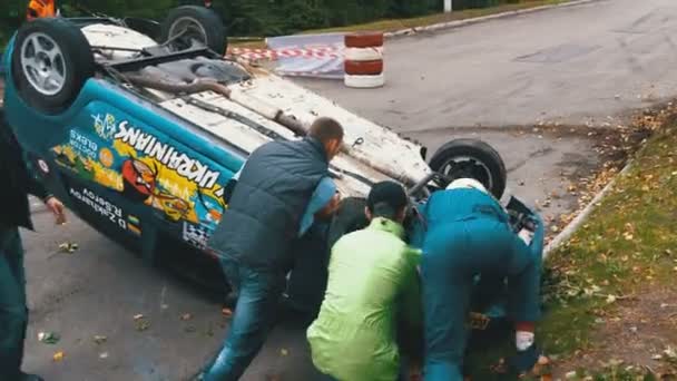 Åskådarna bidra till sväng över rally bilen på taket. Olycka med rallybil — Stockvideo