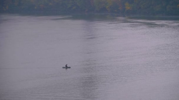 L'homme dans un bateau flotte sur une rivière par une journée d'automne couverte et froide. Pêcheur pêchant dans l'étang — Video