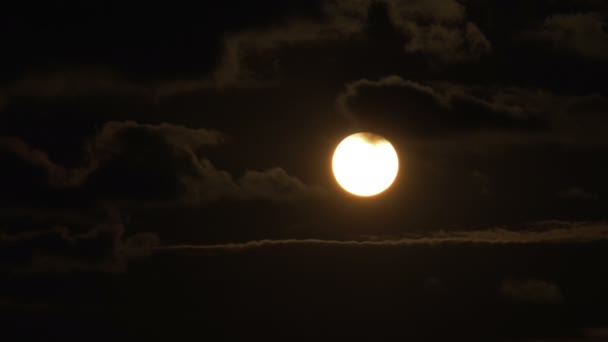 Große rote Sonne bei Sonnenuntergang setzt sich und versteckt sich hinter den Wolken, die am Himmel schweben — Stockvideo