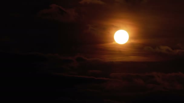 Le grand soleil rouge au coucher du soleil s'assied et se cache derrière les nuages flottant dans le ciel — Video