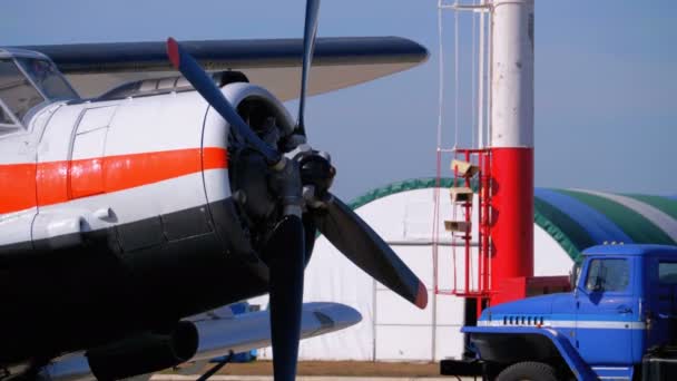 Невеликий літак з Пропелер стоячи на літак автостоянка поблизу Hangar на невеликий аеродром — стокове відео