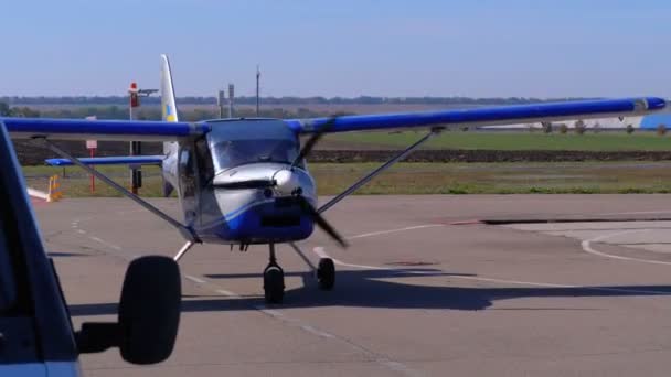 Невеликий приватний літак з обертовим Пропелер, стоячи на стоянки літаків на невеликий аеродром — стокове відео