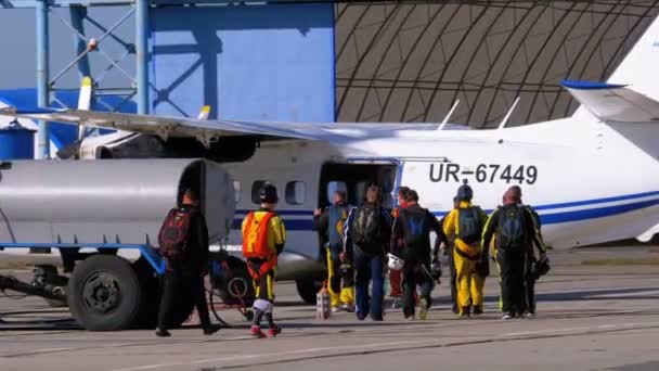 Un gruppo di paracadutisti va all'aereo parcheggiato vicino all'hangar su un piccolo aeroporto — Video Stock