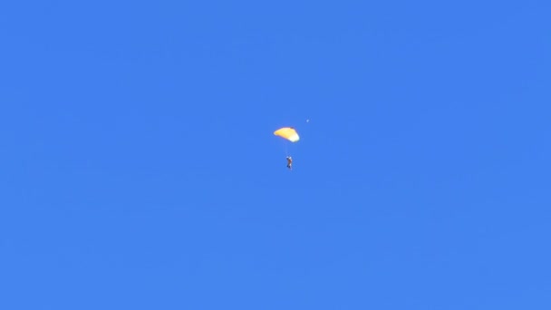 Парашютист летит на парашюте против голубого неба — стоковое видео