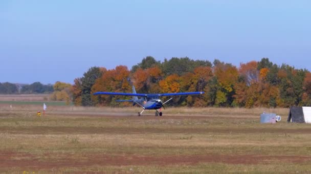 Pequeño avión con una hélice giratoria se mueve a lo largo de una pista con una capa de tierra — Vídeos de Stock