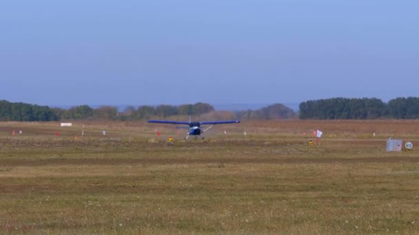 Pequeño avión con una hélice giratoria se mueve a lo largo de una pista con una capa de tierra — Vídeos de Stock