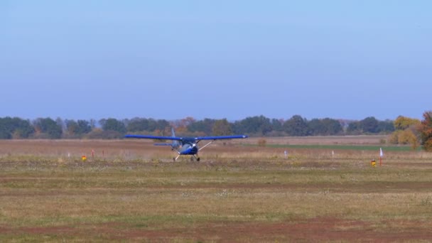 Pequeño avión con una hélice giratoria se mueve a lo largo de una pista con una capa de tierra — Vídeos de Stock