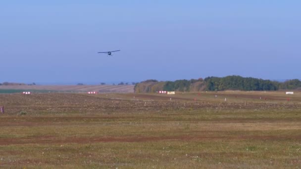 Pequeno avião privado com uma hélice voa sobre a pista com um revestimento de solo — Vídeo de Stock