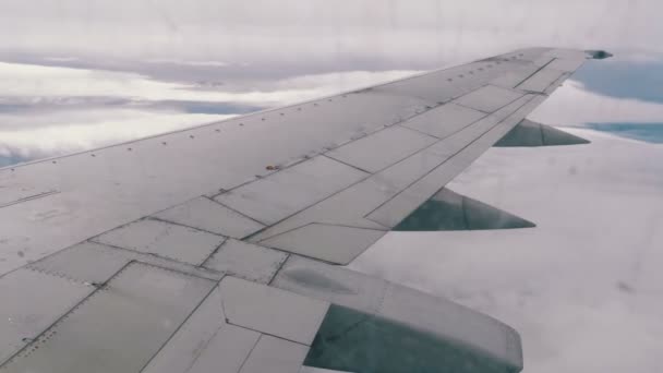 Uitzicht uit het raam van de vliegtuig passagier op de vleugel vliegen boven de wolken — Stockvideo