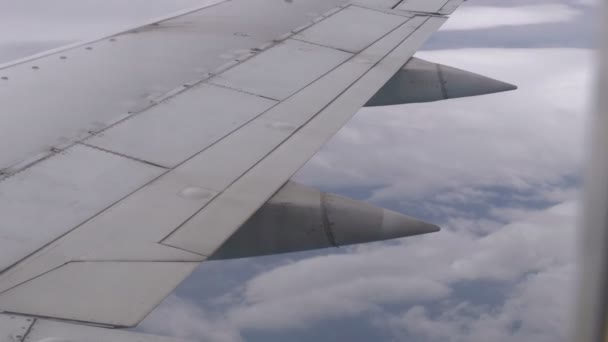 Вид из окна пассажирского самолета на крыло, летящее над облаками — стоковое видео
