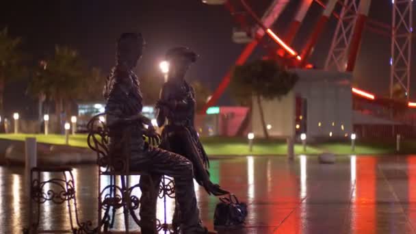 La escultura I, usted y Batumi en la noche en el terraplén de Batumi en el fondo de la noria en la lluvia . — Vídeos de Stock