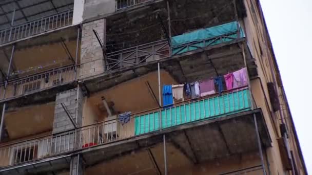 Bairro pobre da cidade. Roupas penduradas em um varal em um prédio durante a chuva — Vídeo de Stock