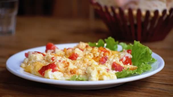 Plaat van de Georgische Omelet met tomaten, kaas en kruiden op een houten tafel in een Restaurant. — Stockvideo