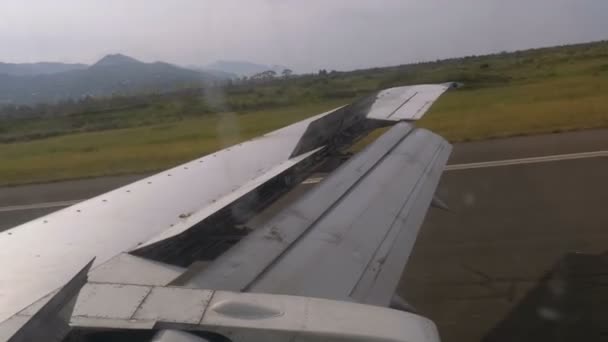 Vista desde la ventana en el ala de un avión que se mueve a lo largo de la pista en el aeropuerto después del aterrizaje — Vídeo de stock