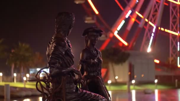 A escultura Eu, você e Batumi à noite no dique de Batumi no fundo da roda gigante na chuva . — Vídeo de Stock