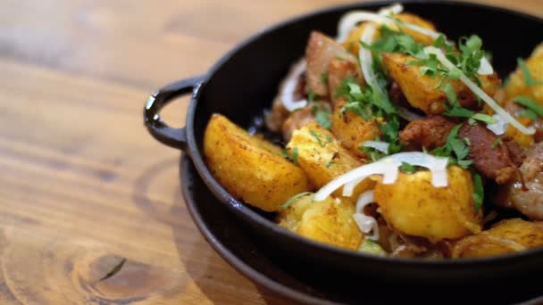 Ojahuri, gebakken aardappelen met het vlees in een koekenpan op een houten tafel in een Georgische restaurant — Stockvideo