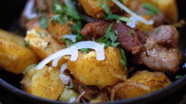Ojahuri, gebakken aardappelen met het vlees in een koekenpan op een houten tafel in een Georgische restaurant — Stockvideo