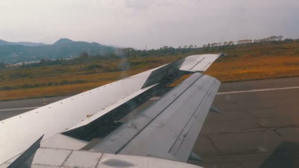 Blick aus dem Fenster auf den Flügel eines Flugzeugs, das sich nach der Landung auf der Landebahn des Flughafens bewegt — Stockvideo