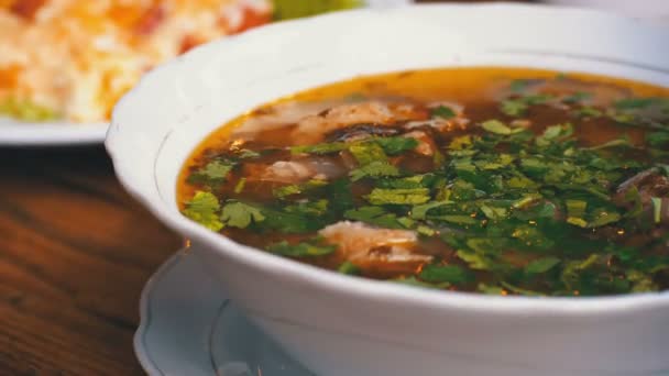 Placa de sopa tradicional georgiana de Khashlama con carne y tortilla con tomates sobre una mesa de madera — Vídeo de stock