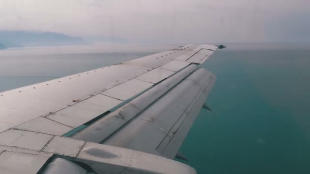 Blick aus dem Fenster des Passagierflugzeugs auf den über dem Meer fliegenden Flügel — Stockvideo