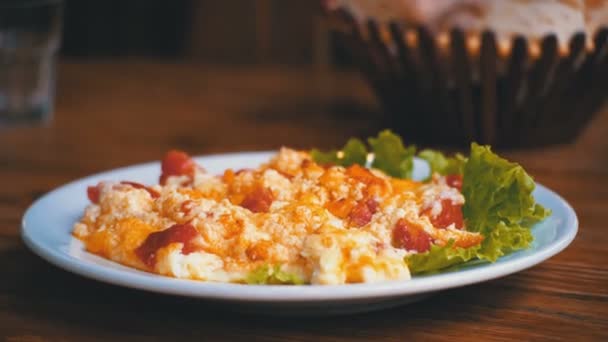 Assiette d'omelette géorgienne aux tomates, fromage et herbes sur une table en bois dans un restaurant . — Video