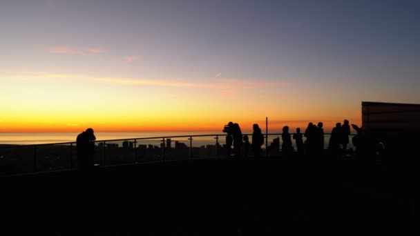 Siluetas de personas en la plataforma de observación en el fondo de la puesta de sol en Batumi — Vídeo de stock
