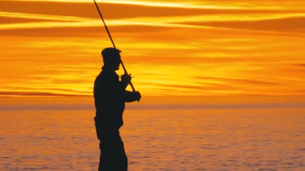 Silhouette of a Fisherman with a Fishing Rod at Sunset over the Sea — Stock Footage Silhouette of a Fisherman with a Fishing Rod at Sunset over the Sea Stock Video
