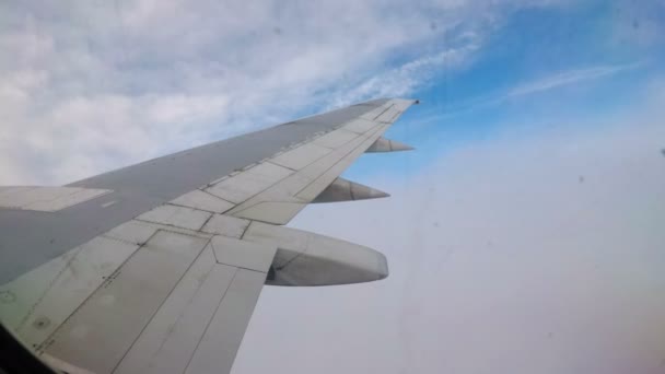 Vista dalla finestra sull'ala di un aereo passeggeri che vola basso sopra le nuvole — Video Stock