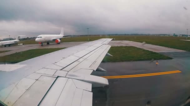 空港の滑走路に沿って移動する飛行機の翼の上の窓からの眺め — ストック動画