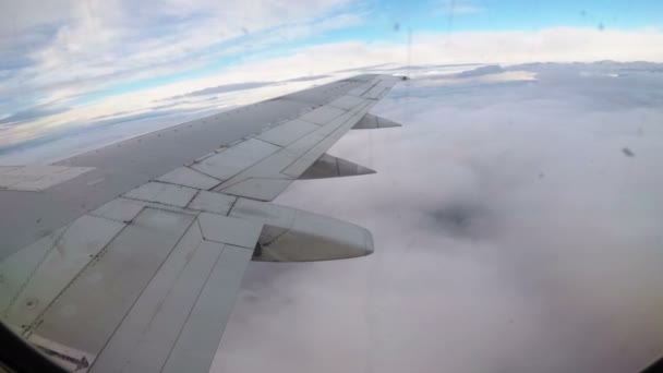 Вид из окна на крыло пассажирского самолета, летящего низко над облаками — стоковое видео