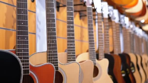 Veel van de akoestische gitaren opknoping in een muziekwinkel. Winkel muziekinstrumenten. — Stockvideo