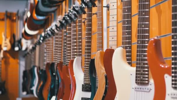 Sok elektromos gitár lógott egy zenebolt. Hangszer bolt — Stock videók