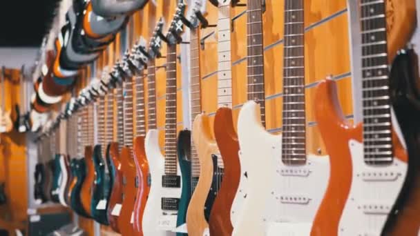 Muchas guitarras eléctricas colgando en una tienda de música. Tienda instrumentos musicales — Vídeo de stock