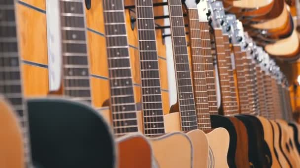 Hel del akustiska gitarrer hängande i en musikaffär. Shop musikinstrument. — Stockvideo