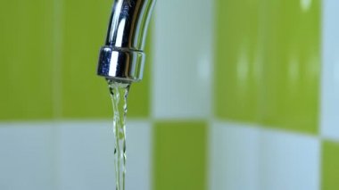 Bir lavabo içine musluk çalışan su. Yakın çekim. Boru banyoya dışarı akan su jetleri makro çekim. Bir musluk su akımları.