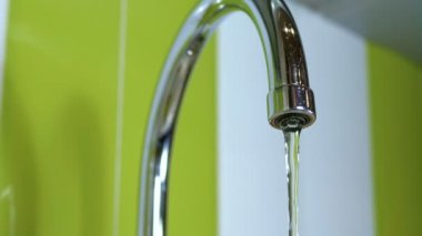 Bir lavabo içine musluk çalışan su. Yakın çekim. Boru banyoya dışarı akan su jetleri makro çekim. Bir musluk su akımları.
