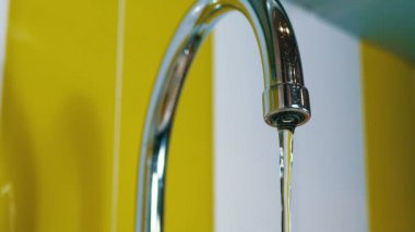 Bir musluk su akımları bir lavabo içine. Yakın çekim. Boru banyoya dışarı akan su jetleri makro çekim. Su musluk çalışan.