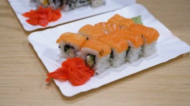 Bir Japon restoranında beyaz tabakta somon suşi rulo