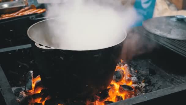 Grande cuba de comida caliente se cocina en las brasas en un mercado de Navidad de la calle — Vídeos de Stock