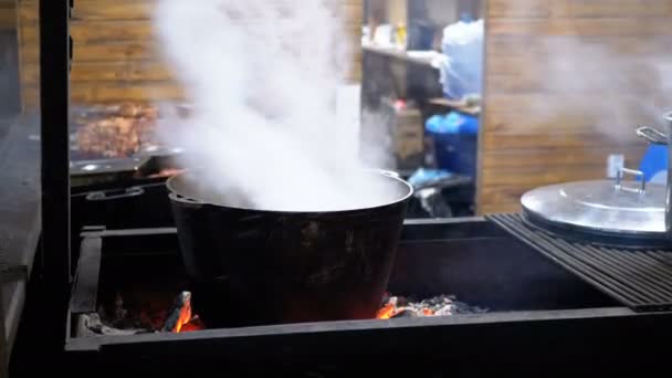Grande cuba de comida caliente se cocina en las brasas en un mercado de Navidad de la calle — Vídeos de Stock