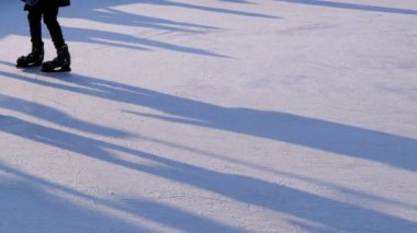 İnsan kalabalığı güneşli bir günde patinaj buz pateni pisti üzerinde vardır. Ağır çekim