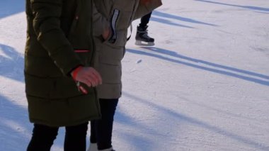 İnsan kalabalığı güneşli bir günde patinaj buz pateni pisti üzerinde vardır. Ağır çekim