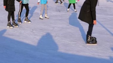 İnsan kalabalığı güneşli bir günde patinaj buz pateni pisti üzerinde vardır. Ağır çekim