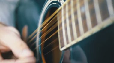 Adam bir arabulucu ile bir akustik gitar çalmak. Ağır çekim