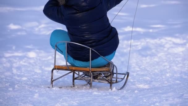 Kinder rodeln einen verschneiten Hügel hinunter. Zeitlupe — Stockvideo
